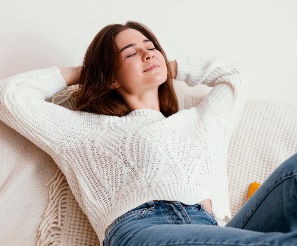 Eine Frau liegt zufrieden auf dem Sofa und geniesst den Moment der Ruhe und Entspannung.
