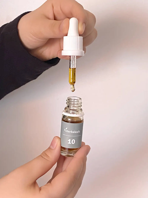 Eine geöffnete Flasche CBD-Öl in der rechten Hand, die Pipette in der linken Hand.